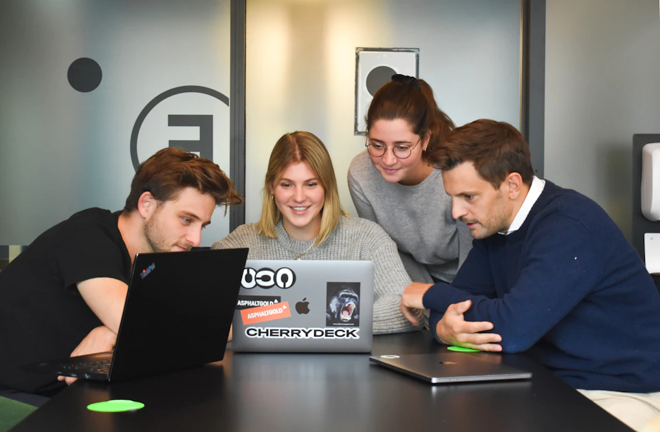 Four people collaborating around a laptop in a modern office